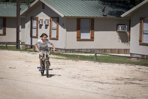 USA, Texas, Boy riding bicycle in suburban area - ABAF001410