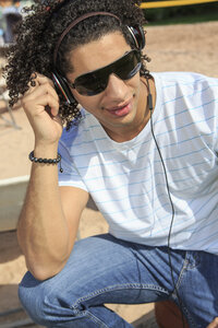 Porträt eines jungen Mannes, der am Strand Musik hört - VTF000296