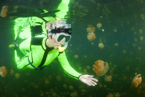 Oceania, Palau, Eik Malk, Female snorkeller watching spotted jellyfish, mastigias papua, in saltwater lake - FGF000031
