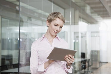 Germany, Munich, Businesswoman in office, using digital tablet - RBYF000509