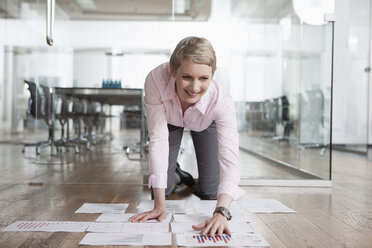 Germany, Munich, Businesswoman in office, sorting papers on floor - RBYF000521