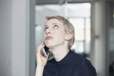 Germany, Munich, Businesswoman in office, using smart phone - RBYF000531