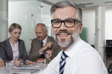 Germany, Munich, Businesspeople in conference room, man in foreground looking to camera - RBYF000628