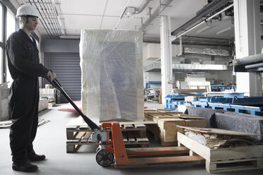 Arbeiter mit Palettenhubwagen in einer Fabrikhalle - SGF000791