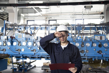 Techniker mit Klemmbrett in einer Fabrikhalle - SGF000784