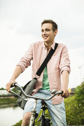 Porträt eines lächelnden jungen Mannes auf einem Fahrrad - UUF001035