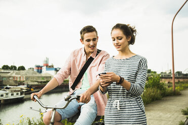 Young couple with bicycle and smartphone - UUF001038