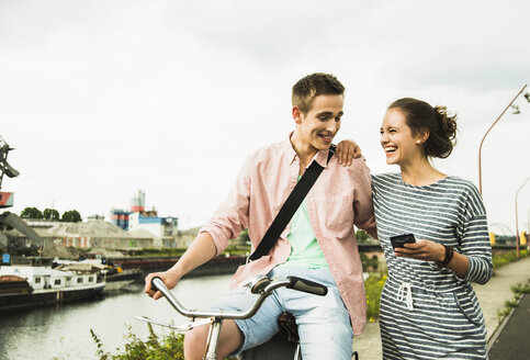Young couple with bicycle and smartphone - UUF001039