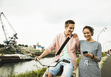 Junges Paar mit Fahrrad und Smartphone - UUF001040