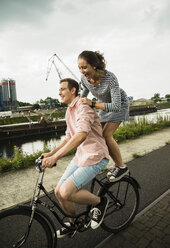 Junges Paar fährt zusammen auf dem Fahrrad - UUF001017