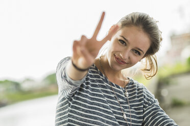 Porträt eines glücklichen Teenager-Mädchens mit Victory-Zeichen - UUF001019