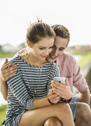 Junges Paar schaut auf Smartphone - UUF001024