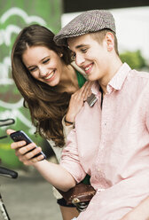 Portrait of young couple having fun with smartphone - UUF001066