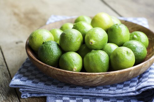 Key limes, Citrus aurantiifolia, in a wooden bowl - HAWF000313