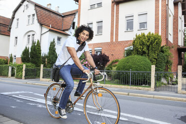 Junger männlicher Student mit Kopfhörern auf einem Rennrad - VTF000293