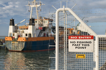 Neuseeland, Nelson, Zaun mit einem Verbotsschild und einem Schiff im Hafen - SHF001493