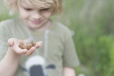 Deutschland, Sachsen, Essbare Schnecke auf der Hand eines Jungen - MJF001291