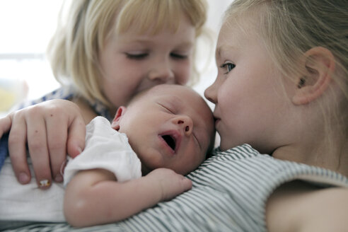 Zwei kleine Mädchen küssen ihren neugeborenen Bruder - SAF000015