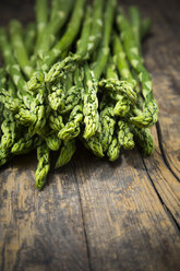 Bunch of green asparagus, Asparagus officinalis, lying on dark wood - LVF001444