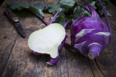 Ganze und halbe blaue Kohlrabi, Brassica oleracea var. gongylodes L. und Messer auf dunklem Holz - LVF001457