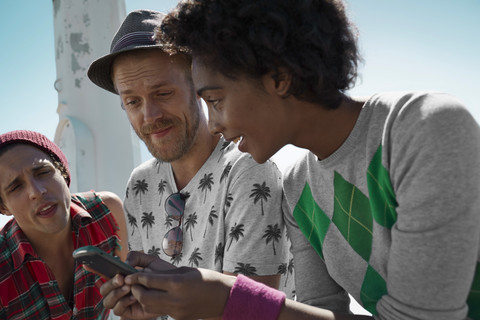 Freunde benutzen Handy im Freien, lizenzfreies Stockfoto