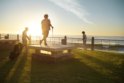 Freunde spielen urbanes Golf an der Küste, lizenzfreies Stockfoto