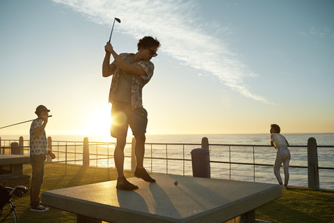 Freunde spielen urbanes Golf an der Küste, lizenzfreies Stockfoto