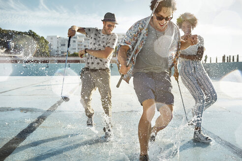 Friends playing urban golf in empty swimming pool - VV000118