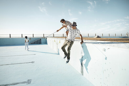 Friends playing urban golf in empty swimming pool - VVF000143