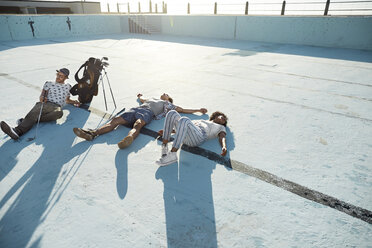 Friends lying in empty swimming pool with golf clubs - VV000120