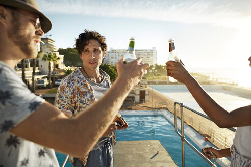 Friends drinking beer on highboard of a swimming pool - VV000146