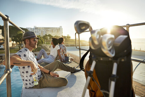 Urban golfers sitting on highboard of a swimming pool - VV000147