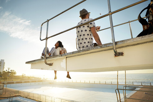 Urbane Golfer sitzen auf dem Highboard eines Swimmingpools - VV000148