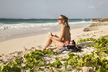 Caribbean, Barbados, woman sitting by the beach - SKF001559