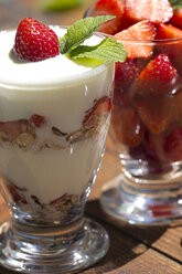 Strawberries in a glass and strawberries with yogurt and muesli in a glass, garnished with lemon balm - YFF000184