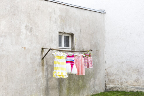 Deutschland, düsterer Hinterhof mit Kinderkleidern, die an der Kleiderstange hängen - DR000693