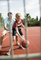 Germany, Mannheim, Father and son playing basket ball - UUF001176