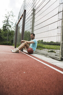 Deutschland, Mannheim, Mann sitzt auf Sportplatz - UUF001107