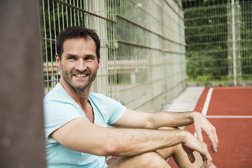 Germany, Mannheim, Man sitting on sports field - UUF001108