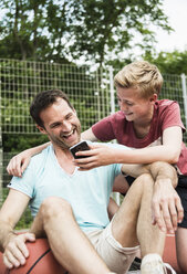 Germany, Mannheim, Father and son looking at smart phone - UUF001111