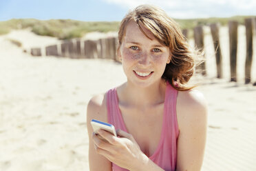 Porträt einer Frau mit Smartphone am Strand - MFF001131