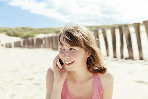 Porträt einer Frau, die mit ihrem Smartphone am Strand telefoniert, lizenzfreies Stockfoto