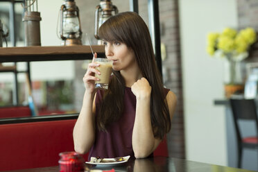 Portrait of young woman drinking milk coffee in cafe - GDF000335