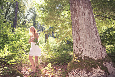 Portrait of a young woman wearing white dress standing in the forest - VTF000313