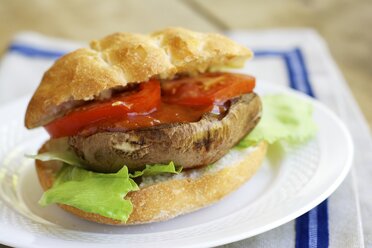 Gegrillter Portobello-Pilz-Burger mit Tomate und Kopfsalat auf einem Teller - HAWF000334