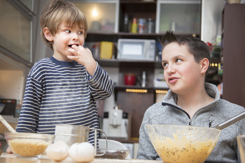 Two brothers baking a cake together at home stock photo