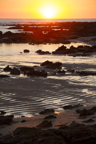 Australien, Westaustralien, Sonnenuntergang an einem Fels- und Sandstrand bei Broome, lizenzfreies Stockfoto