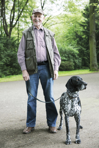 Älterer Mann geht mit seinem Deutsch-Kurzhaar-Zeiger im Stadtpark spazieren, lizenzfreies Stockfoto