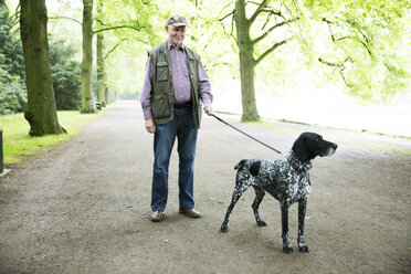 Senior man walking with his German Shorthaired Pointer in city park - JATF000735