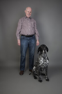 Älterer Mann mit seinem Deutsch-Kurzhaar-Zeiger vor grauem Hintergrund - JATF000737